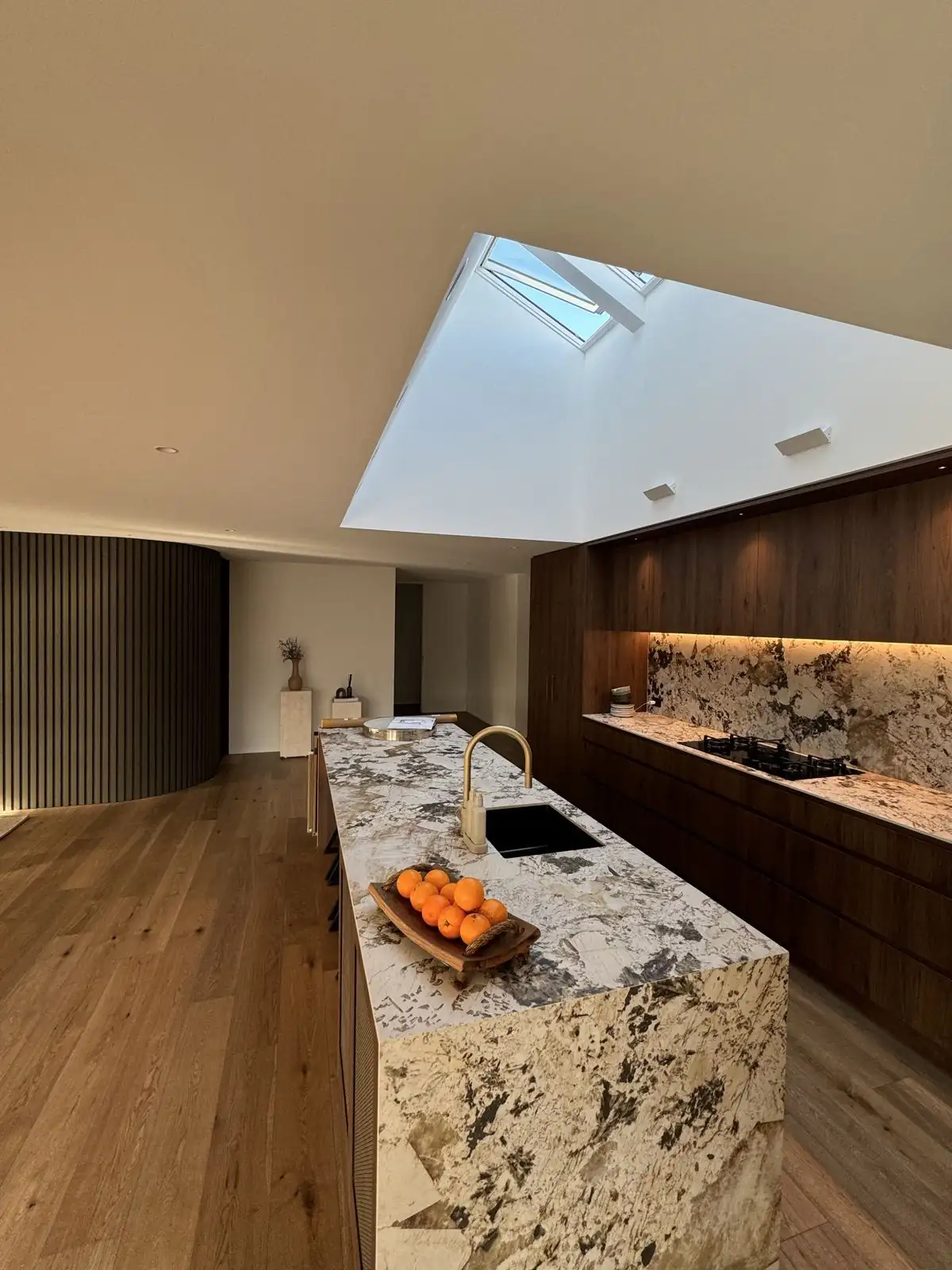 Kitchen with stone island, dark cabinetry and the slatted wall beyond
