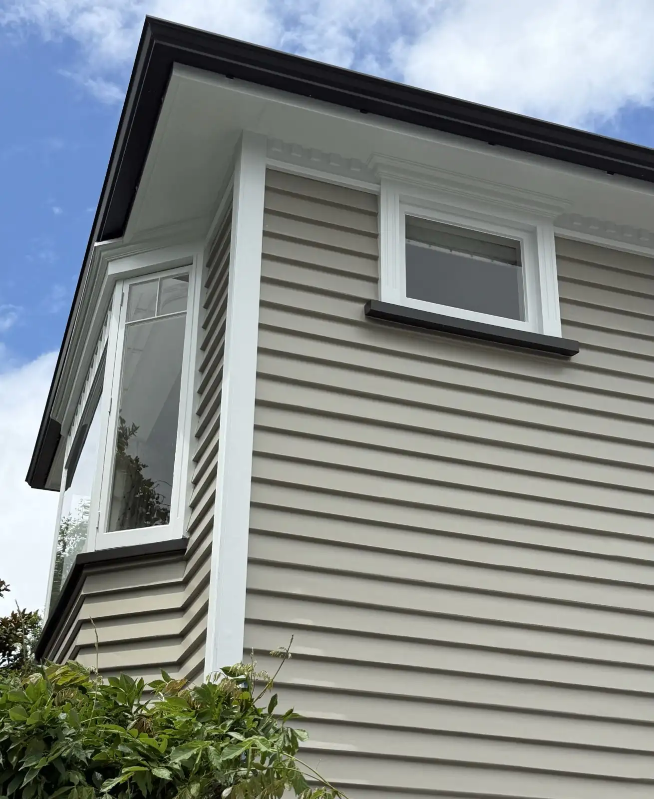 Corner of the villa showing the upper-storey bay window and dark roof edge