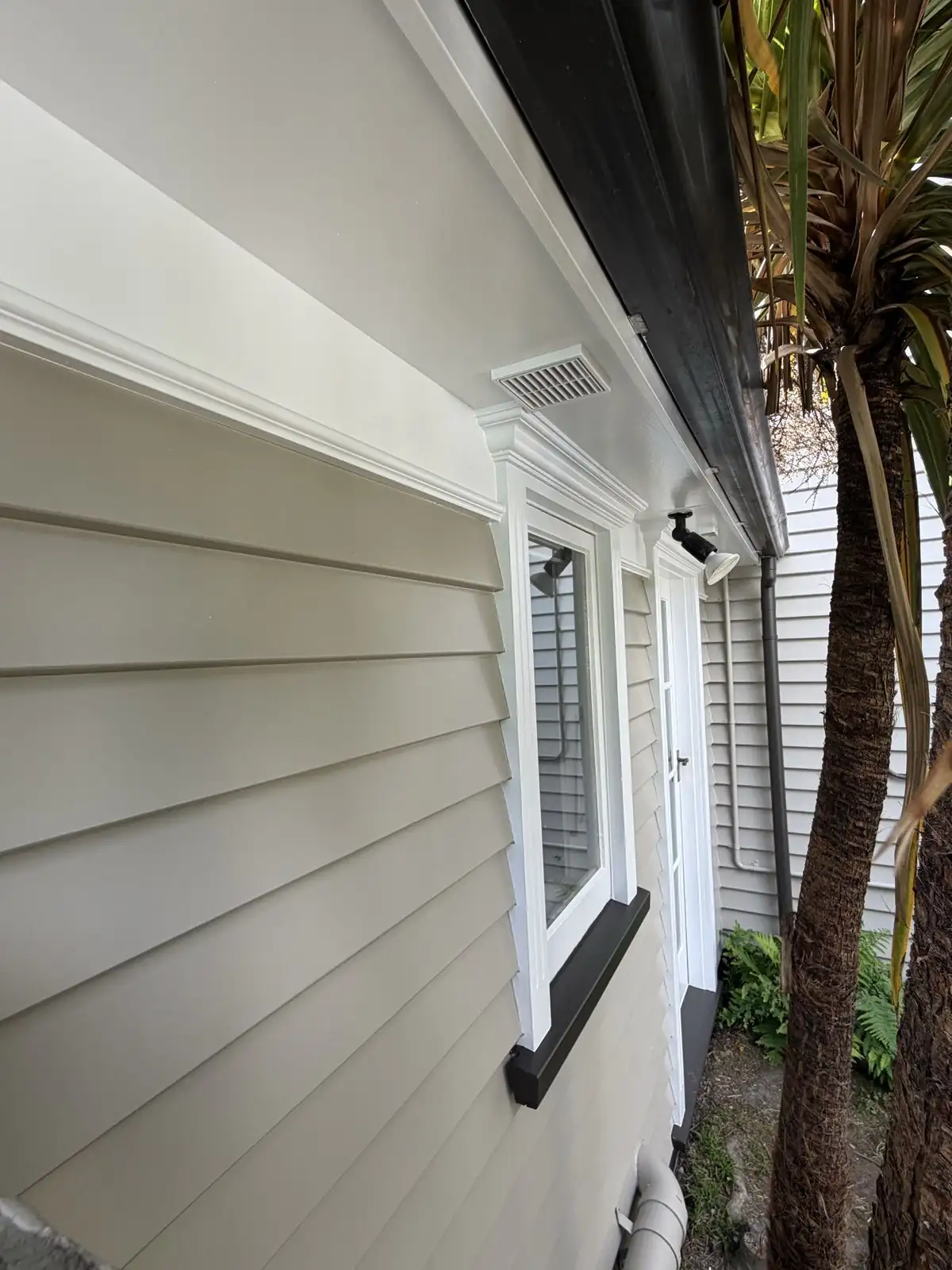 Detail of the weatherboards, white window trim and dark bottom board