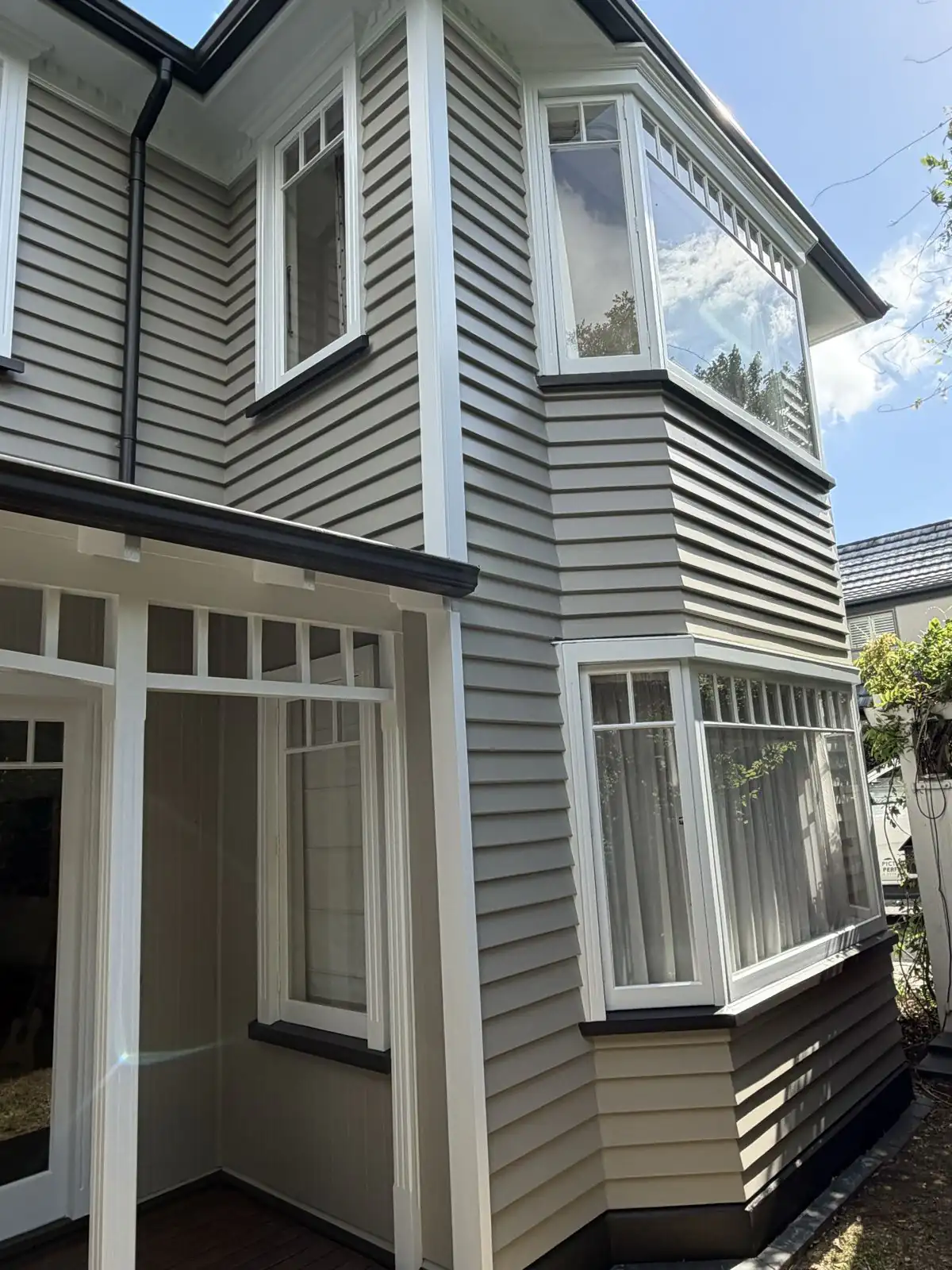 Two-storey weatherboard villa on Idris Road with fresh stone-coloured cladding and white trims
