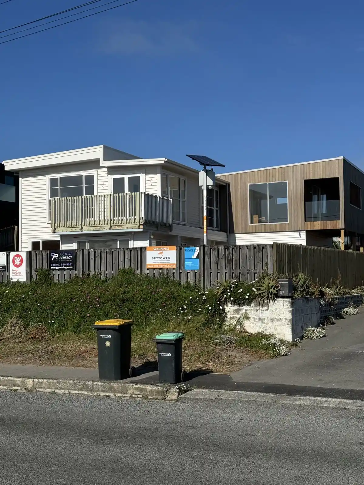 The finished house from the street with white weatherboards and cedar cladding