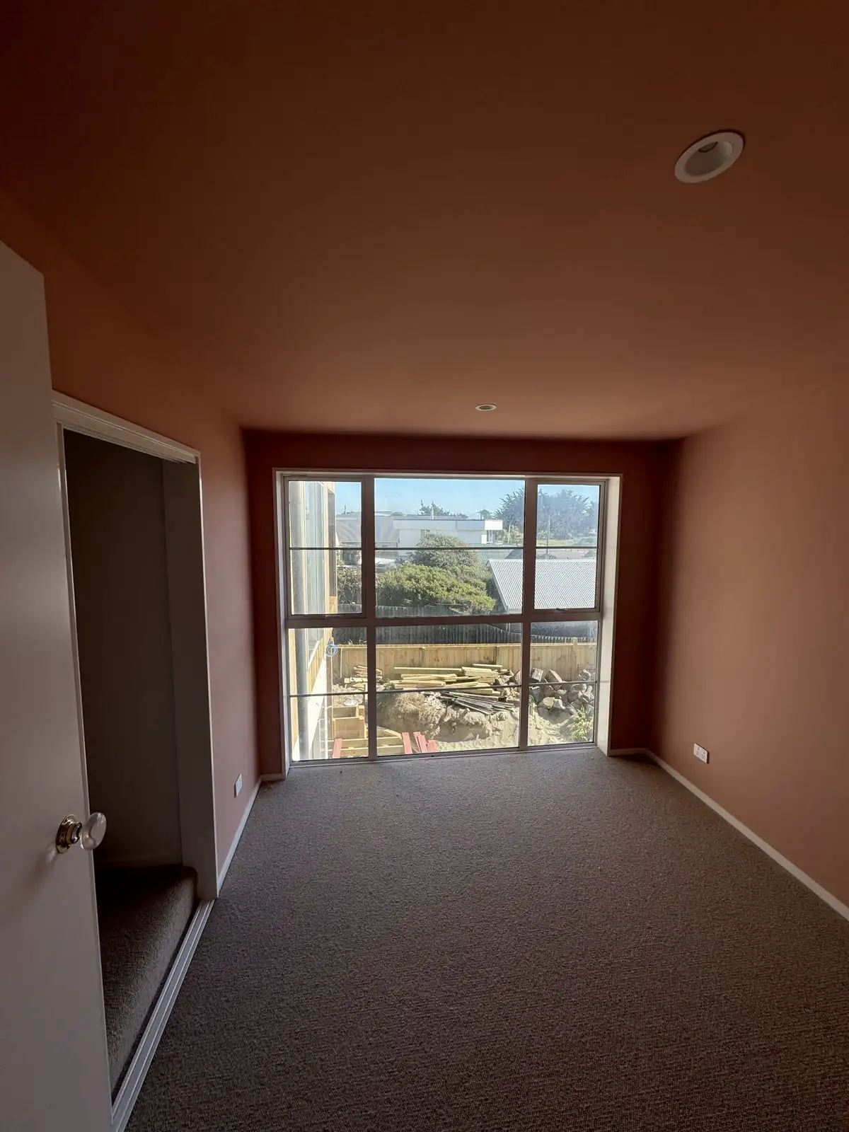 Main bedroom finished in a warm rust colour with sea views
