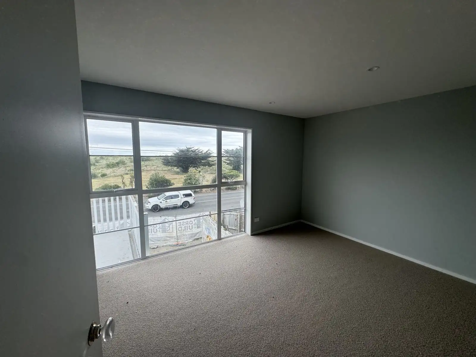 Living room in deep sage green with a view across the road to the dunes