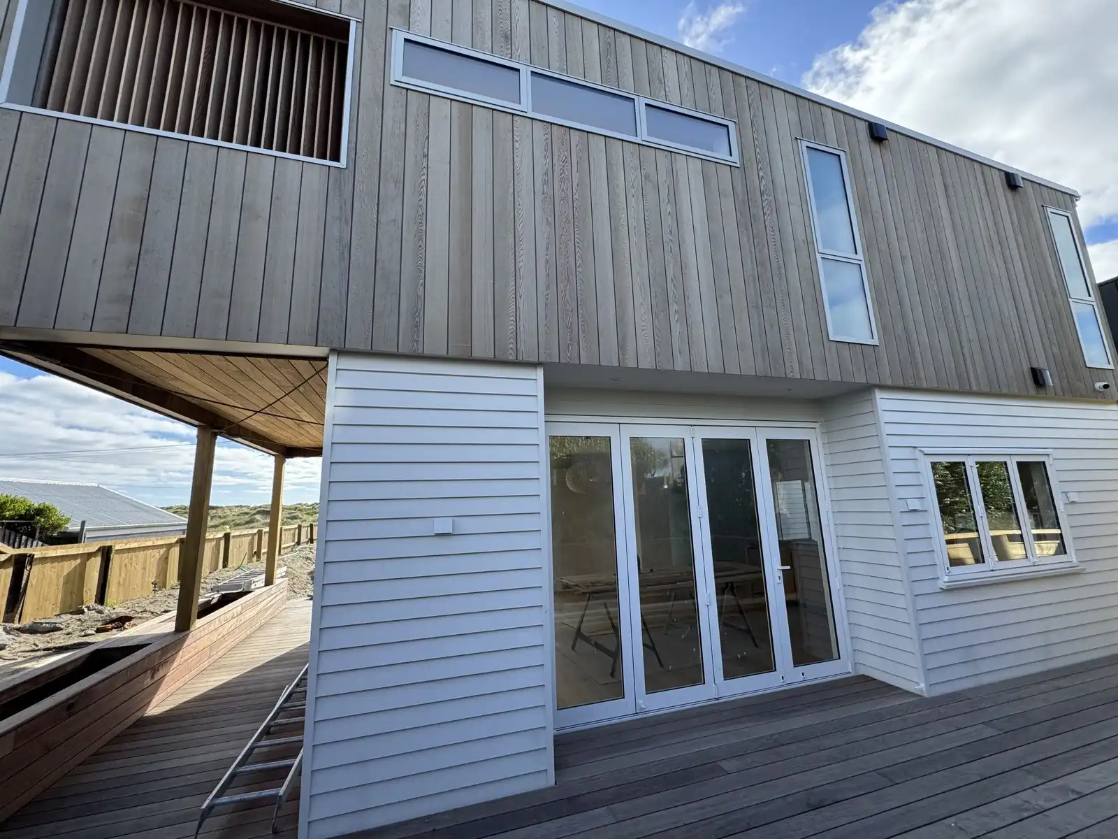 Finished beachfront home on Marine Parade with white weatherboards, cedar cladding and a new deck