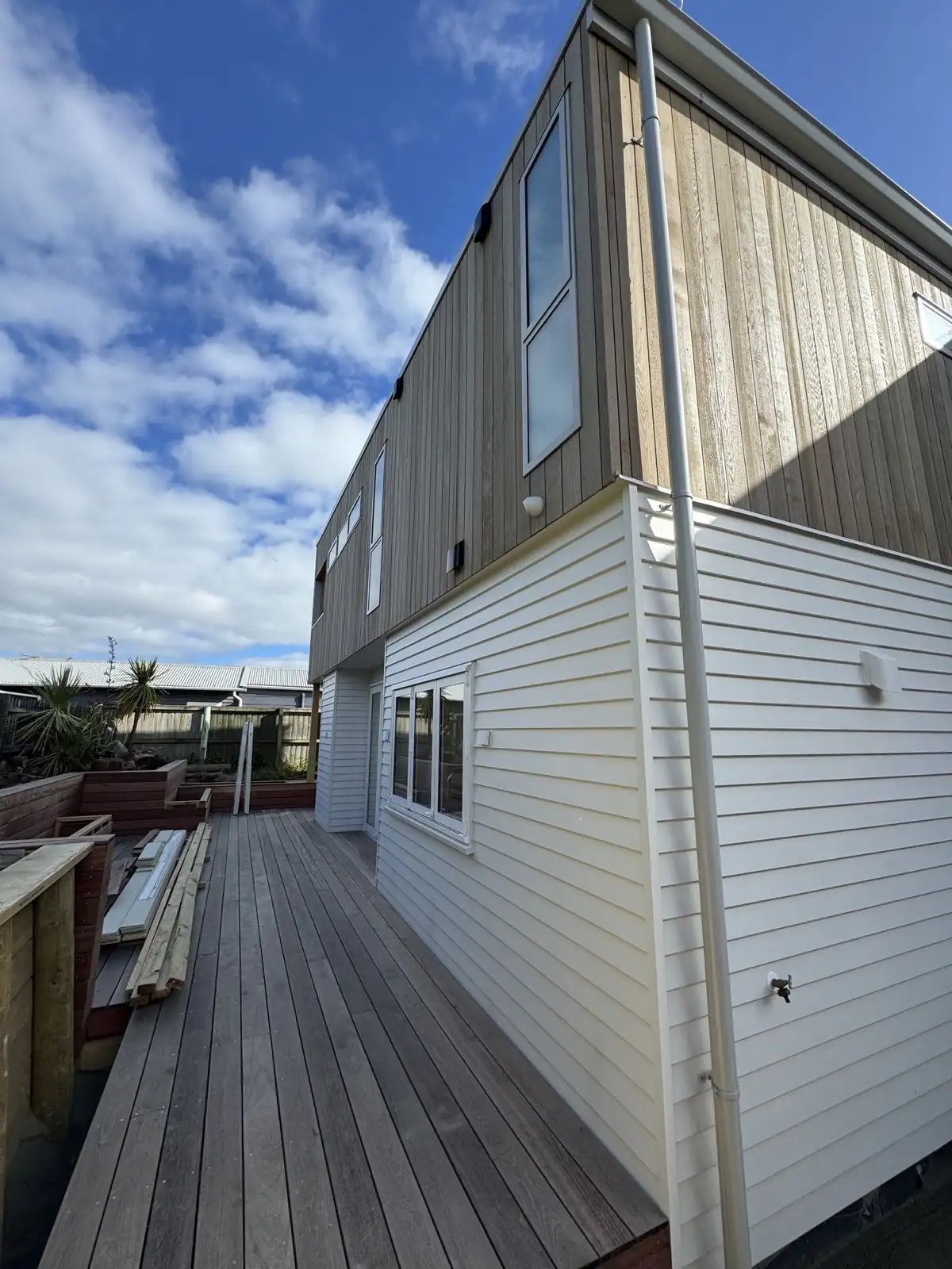 Side of the house showing the white weatherboards and cedar-clad upper storey
