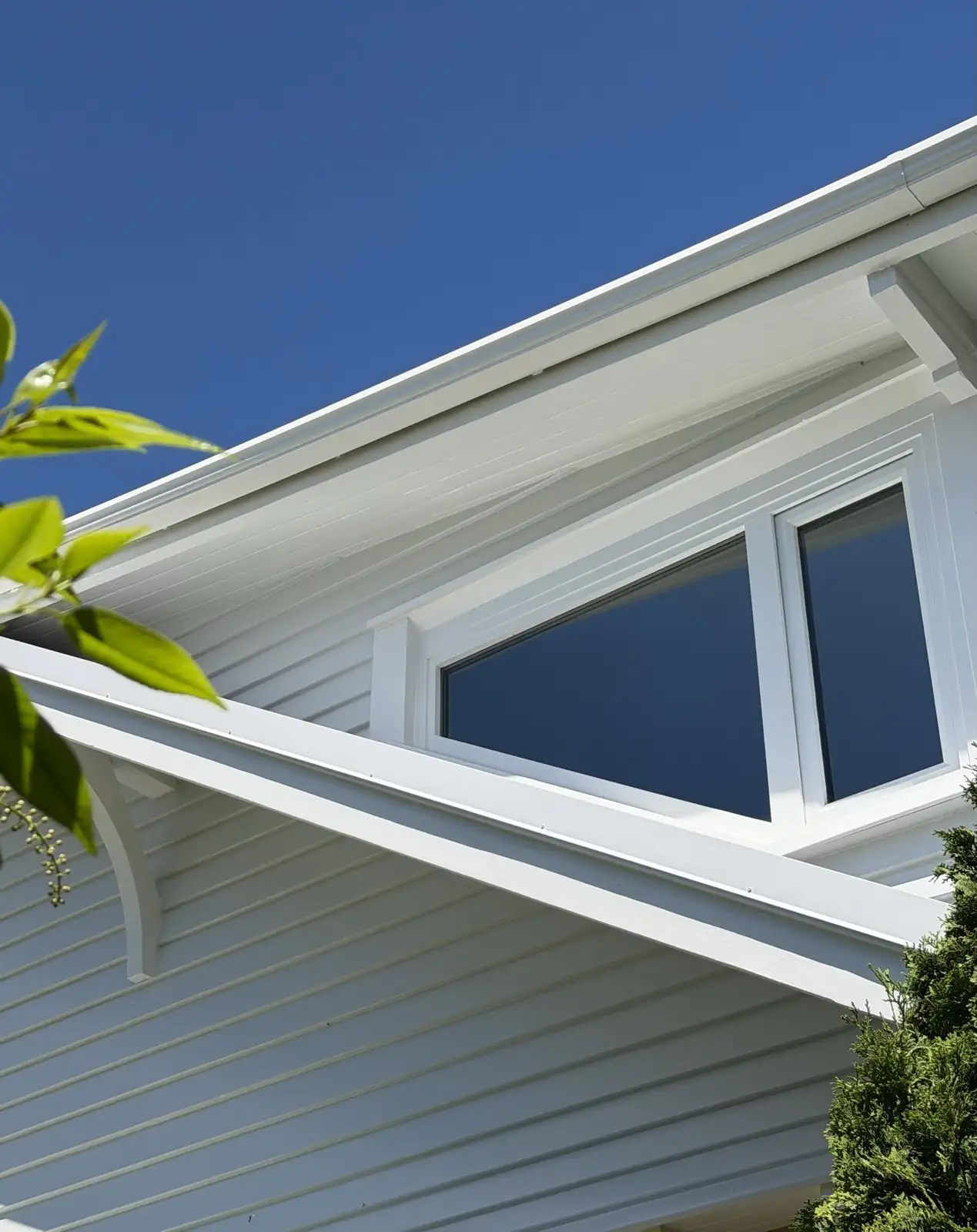 Detail of the eaves and rafter tails against a blue sky