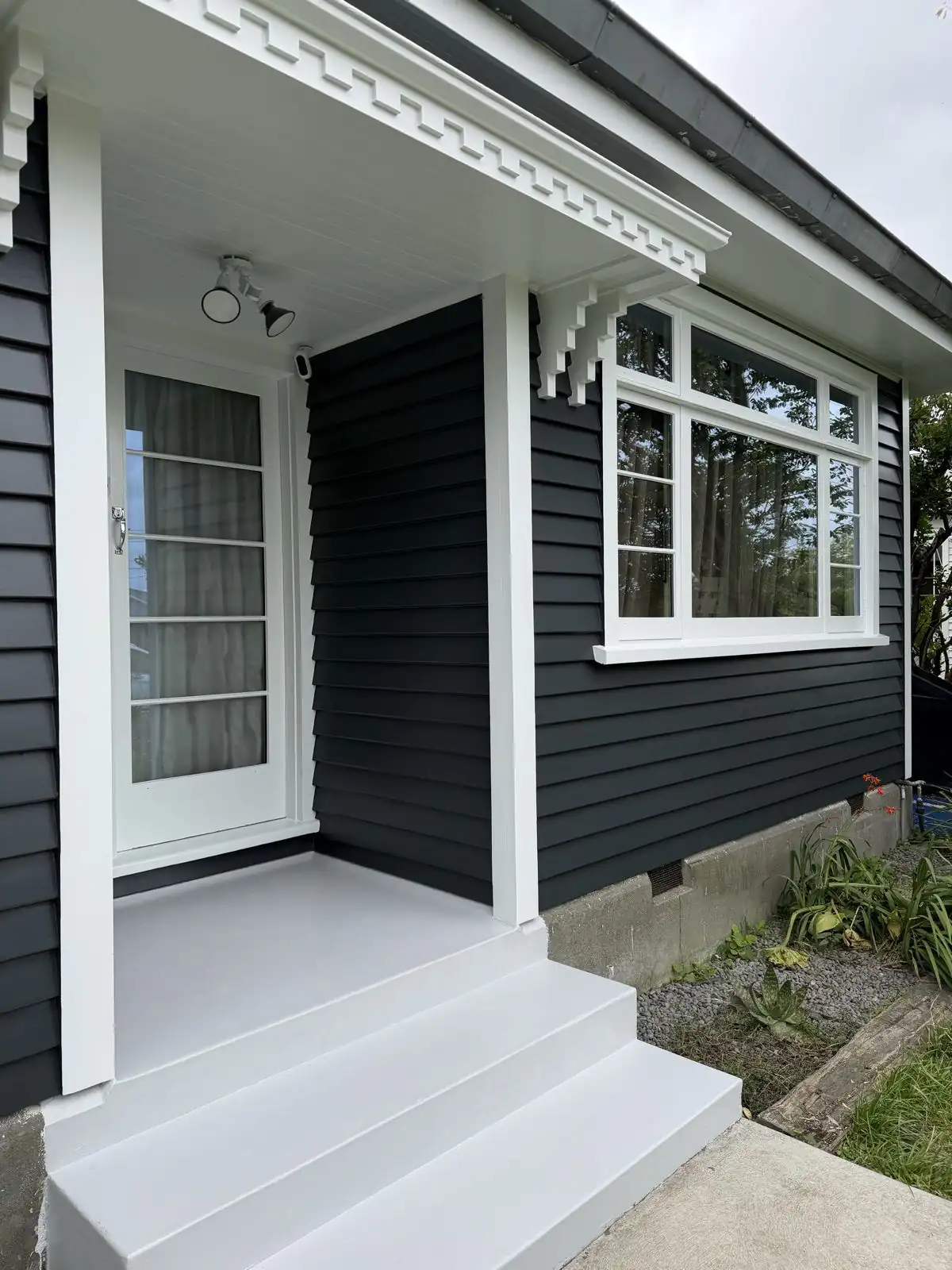 Charcoal weatherboards and white windows along the front porch