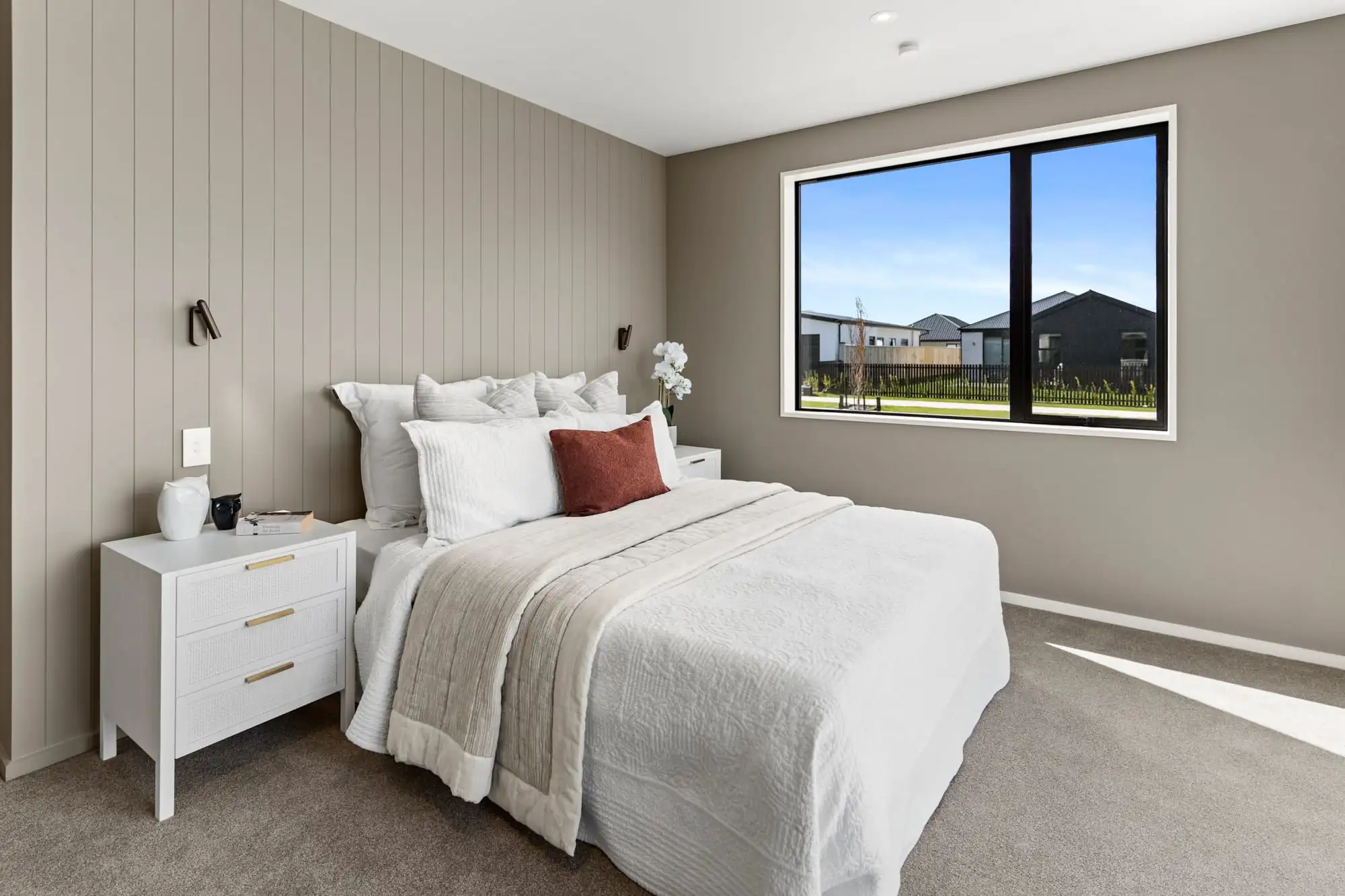 Main bedroom with a greige panelled feature wall and wall lights behind the bed