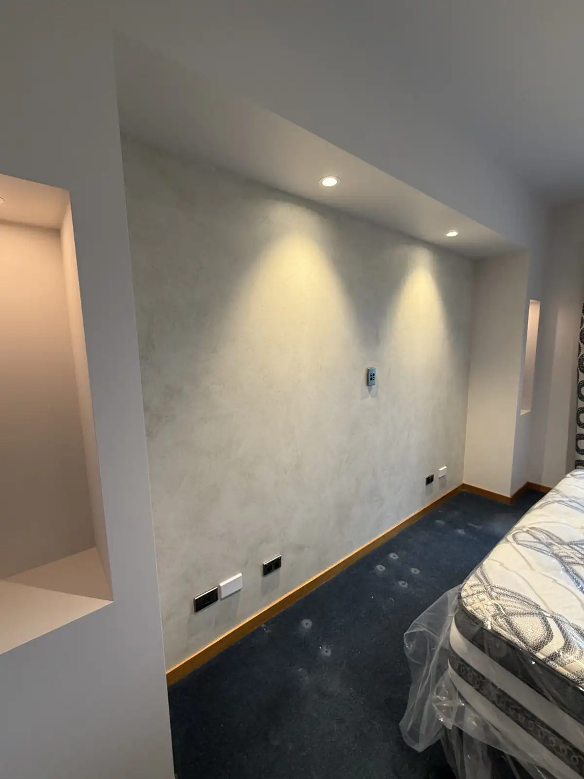 Polished plaster feature wall with recessed lighting in a bedroom