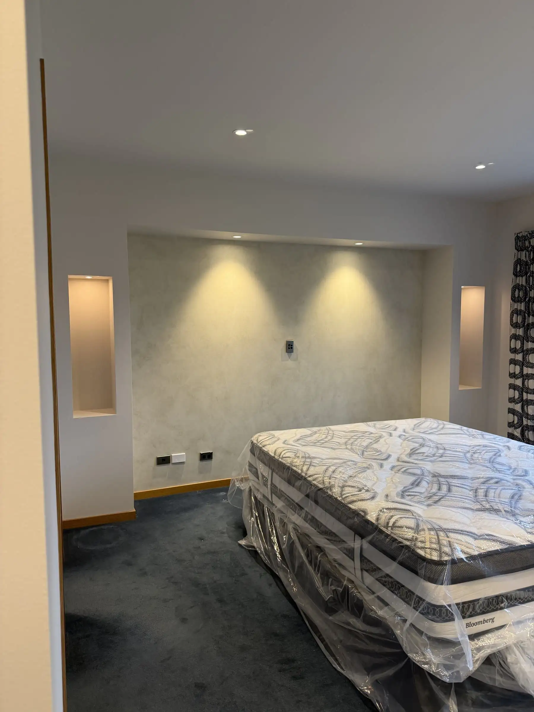 Bedroom feature wall in a polished plaster specialty finish, lit by downlights